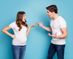 Pregnant couple talking and holding hands while dealing with relationship challenges.