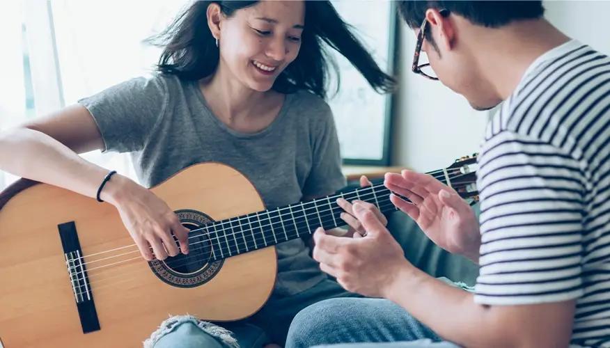 Couple enjoying guitar practice together at home