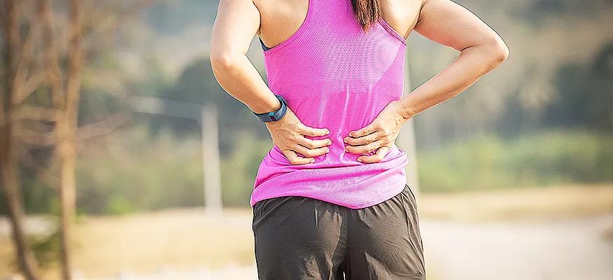 Woman holding lower back in pain, showing signs of chronic back discomfort