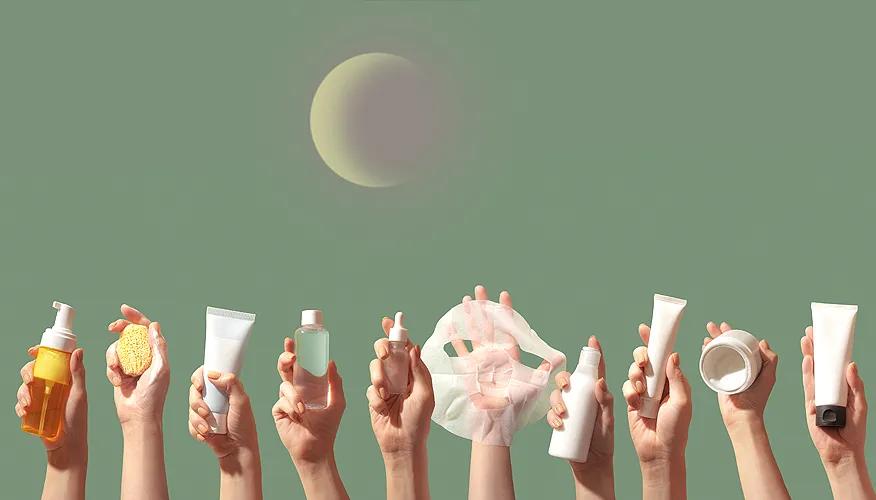 Hands holding various skincare products against green background